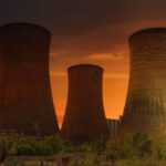 Atomic Habits - Exterior of huge cooling towers located in contemporary atomic power plant against bright setting sun under dramatic dark sky