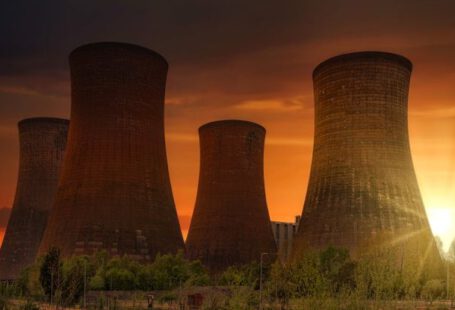 Atomic Habits - Exterior of huge cooling towers located in contemporary atomic power plant against bright setting sun under dramatic dark sky