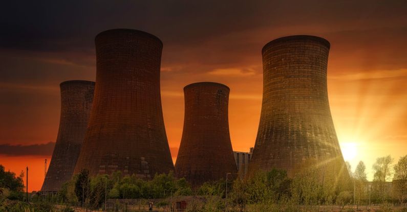 Atomic Habits - Exterior of huge cooling towers located in contemporary atomic power plant against bright setting sun under dramatic dark sky