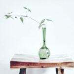 Becoming - green glass vase on brown wooden table