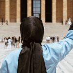 Educated - A woman in a hijab holding a graduation cap