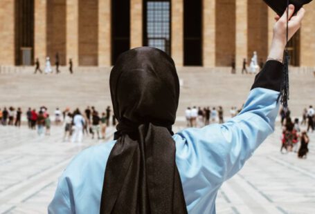 Educated - A woman in a hijab holding a graduation cap