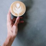 DAMN. - Person Holding Cappuccino on White Ceramic Cup