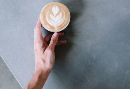 DAMN. - Person Holding Cappuccino on White Ceramic Cup