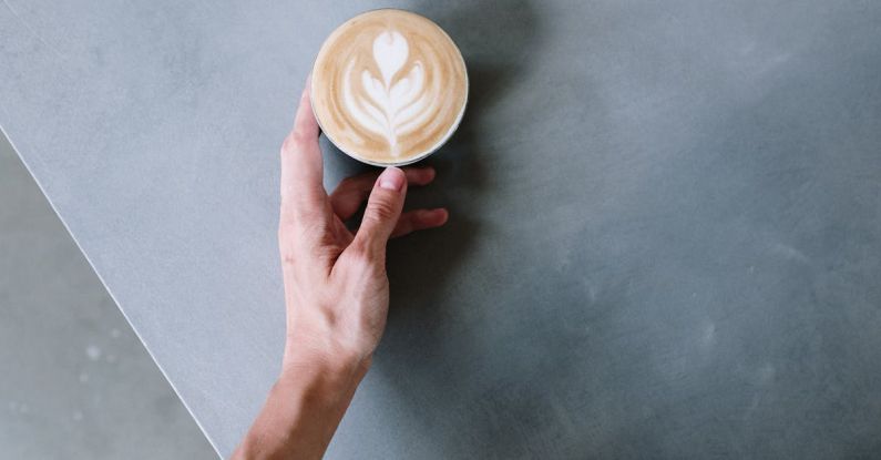 DAMN. - Person Holding Cappuccino on White Ceramic Cup