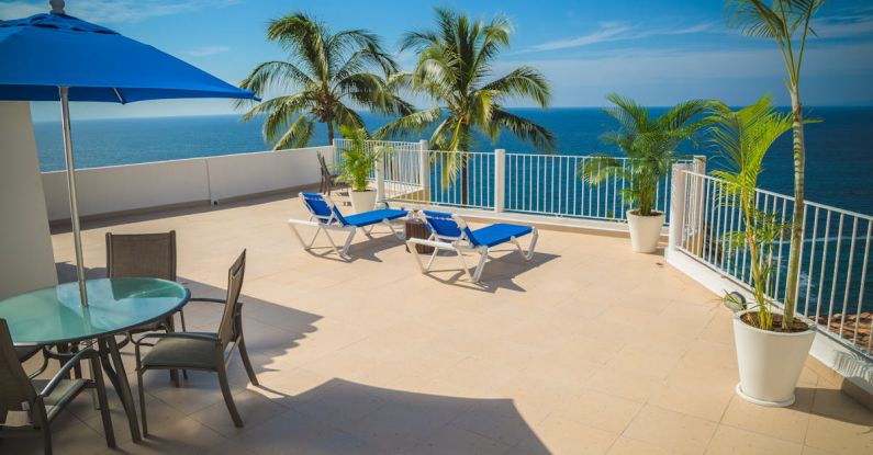 Handmaid's Tale - Blue Loungers on Beige Balcony Beside Sea Landscape Photography