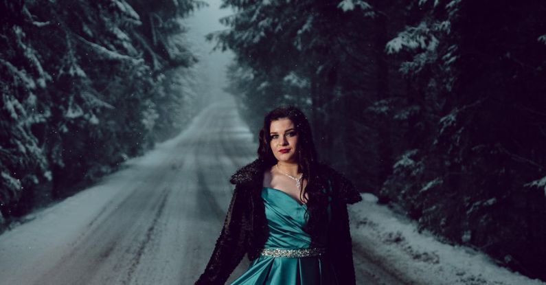 Silk Roads - Model Wearing a Turquoise Satin Dress Posing on a Forest Road in Winter at Dusk